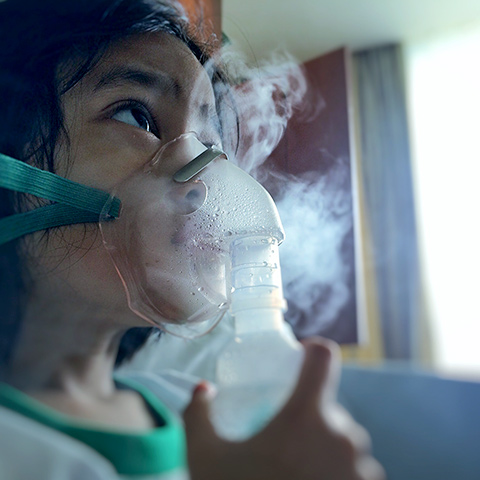 Girl with a nebulizer inhaling aerosolized medicine