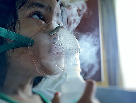 Girl with a nebulizer inhaling aerosolized medicine
